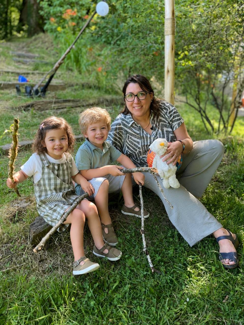 Chrystel assise dans l'herbe avec deux jeunes enfants pendant une garde en extérieur