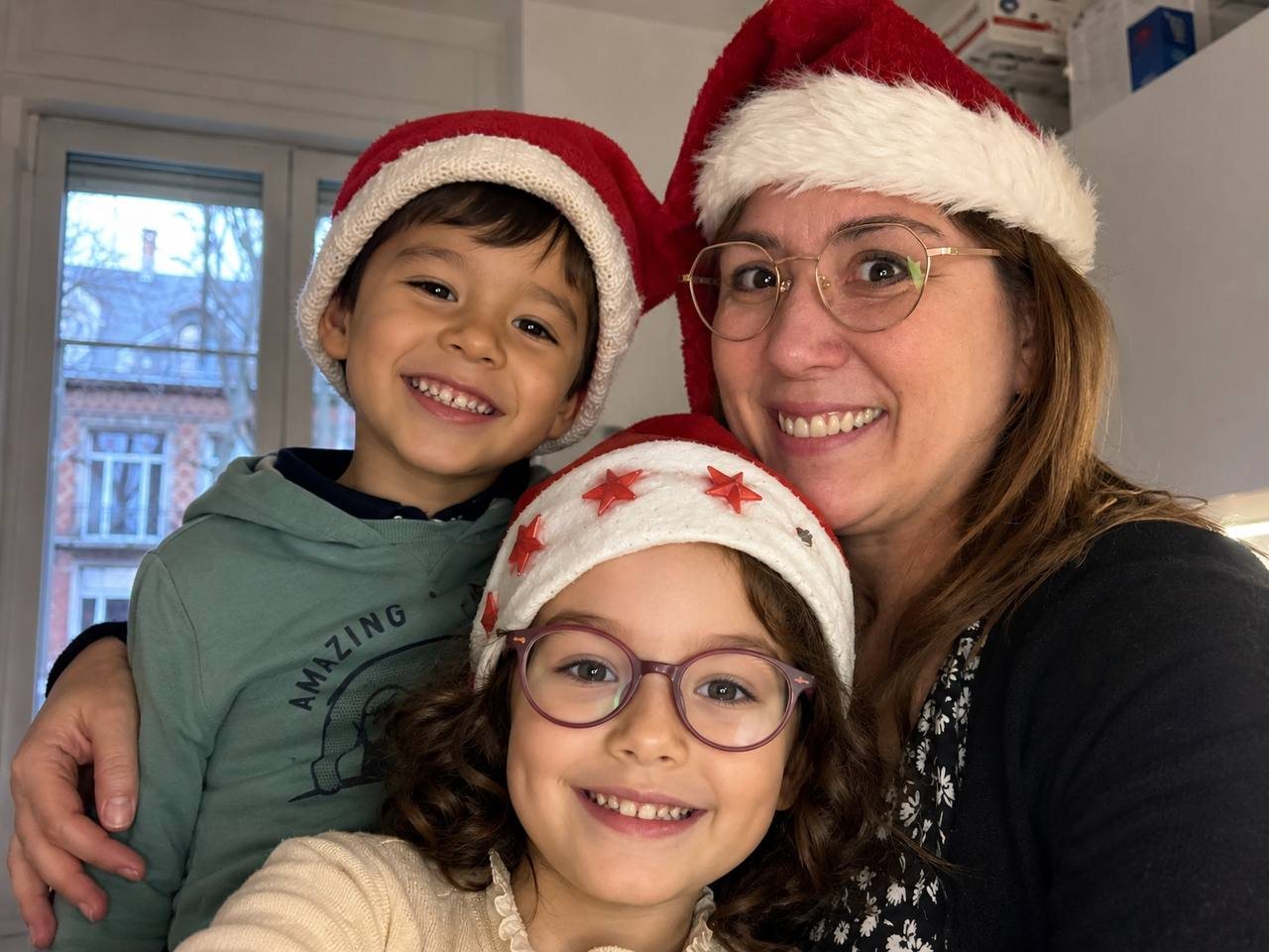 Chrystel et deux enfants coiffés de bonnets de Noël